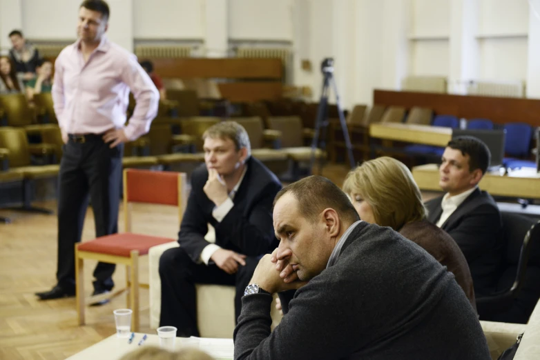 men and women at an meeting sitting on separate chairs