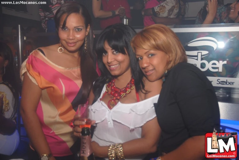 three women posing for a po while holding a bottle