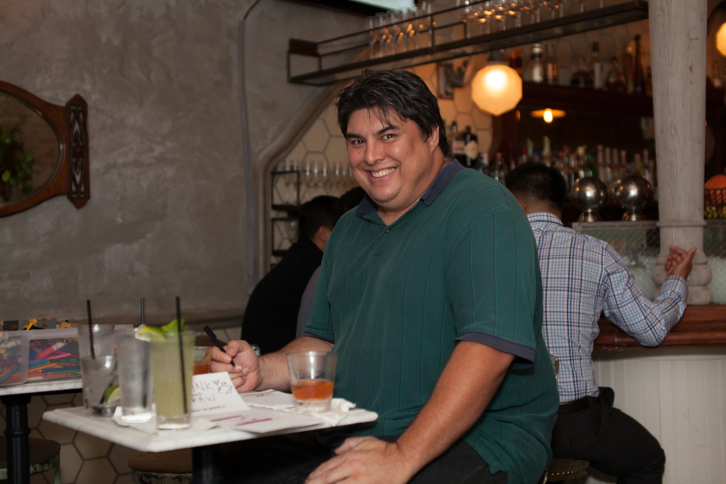 a man in a restaurant sitting at the bar writing on a paper