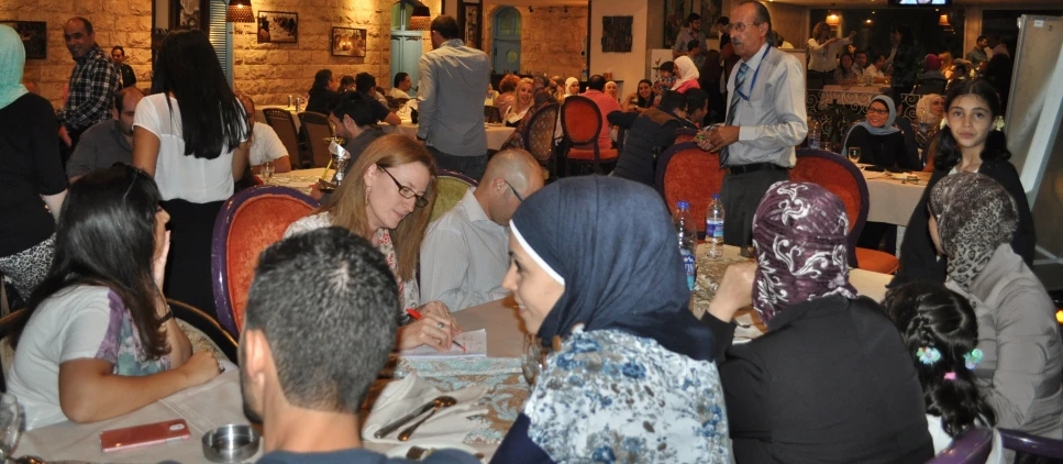 many people gathered around a table with a white board