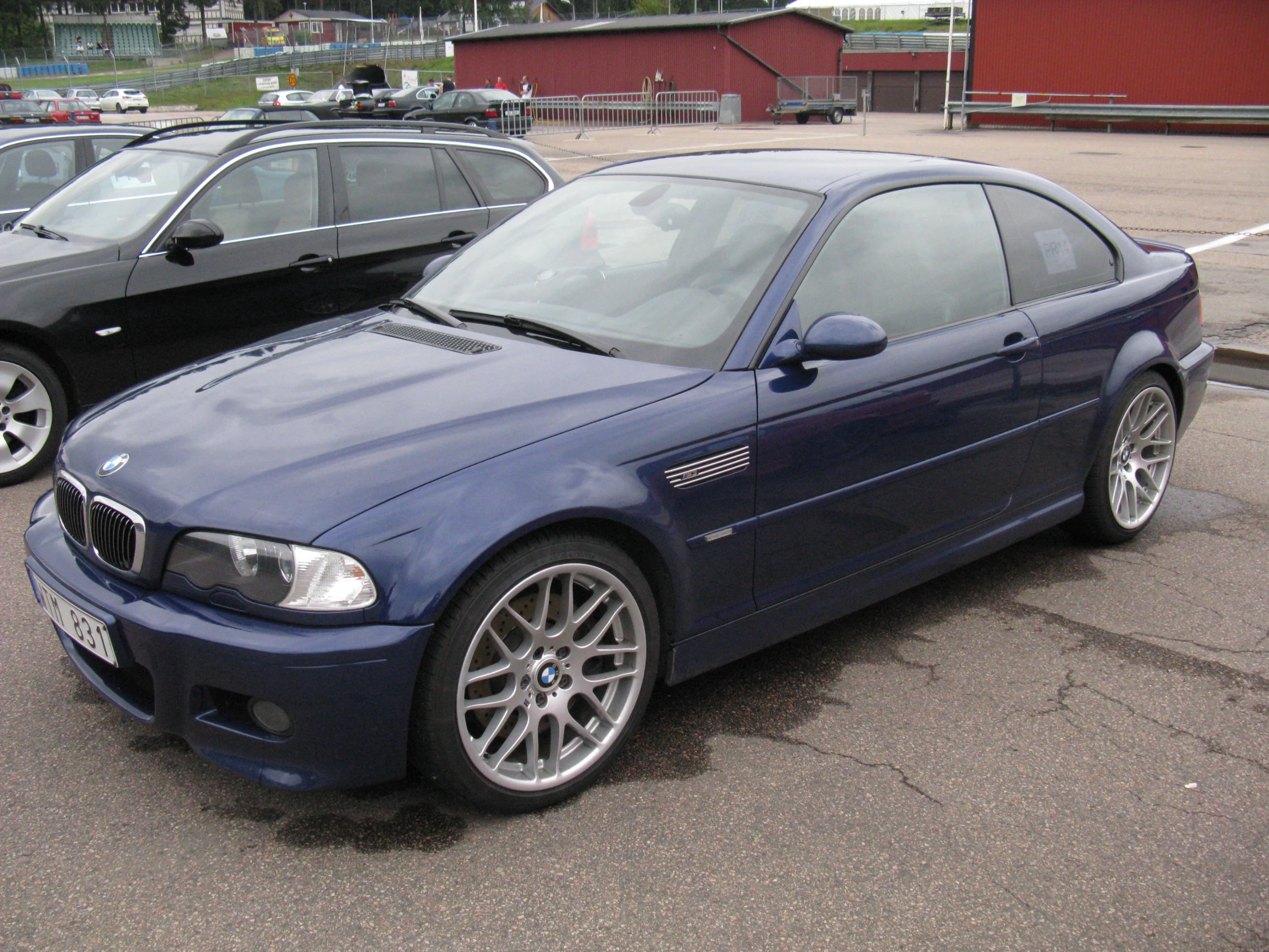 the blue car is parked on the pavement near several other cars