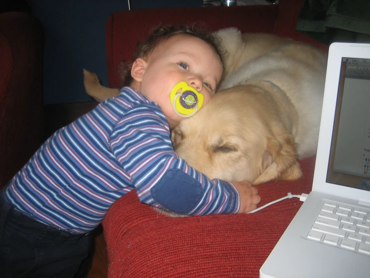 a small child in a red chair next to a dog with pacifier