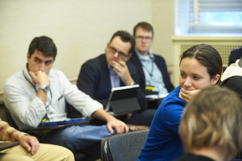 several people sitting in a row looking at laptops