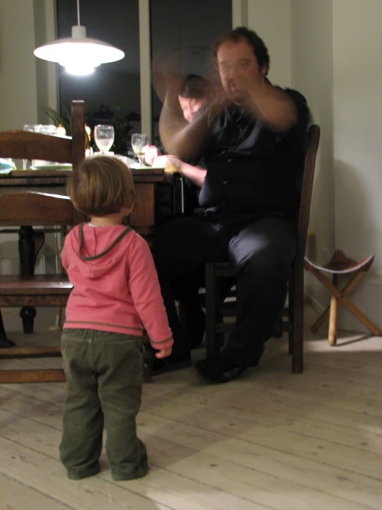 a man sitting in front of a small child on top of a wooden floor