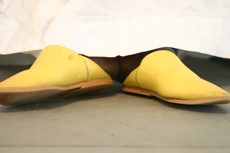 a pair of yellow slippers sitting underneath a bed