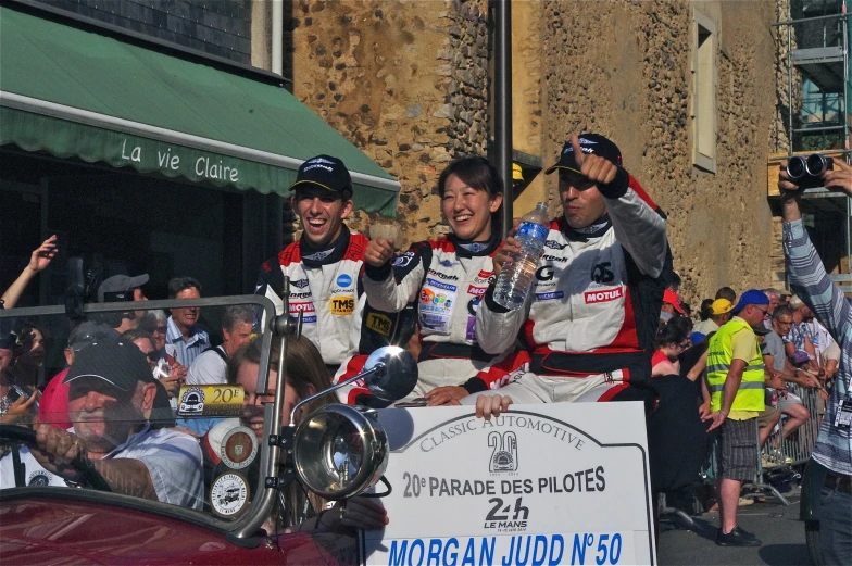 three men who are posing on top of a car