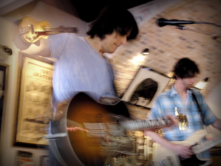 two men playing guitars in a room