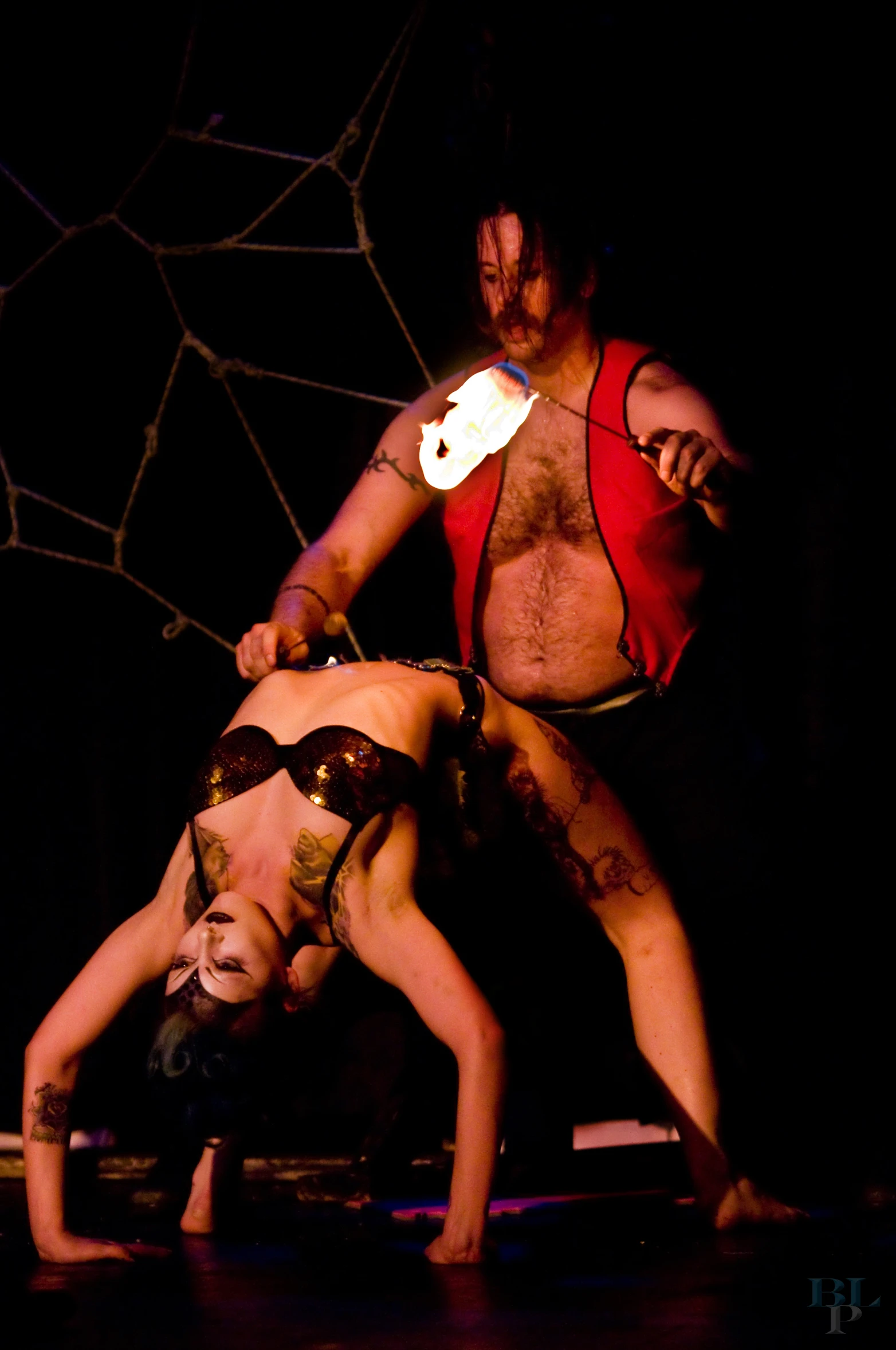 a couple of men performing in the dark with one wearing glasses