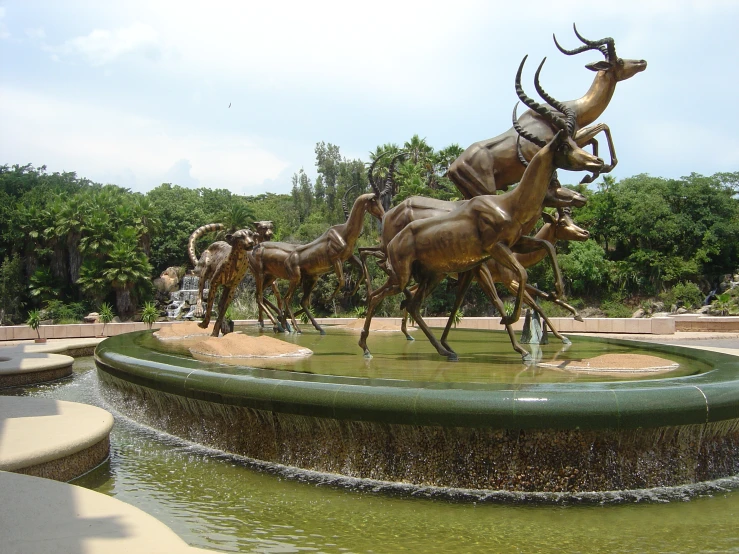 a group of bronze sculptures standing in the middle of a park