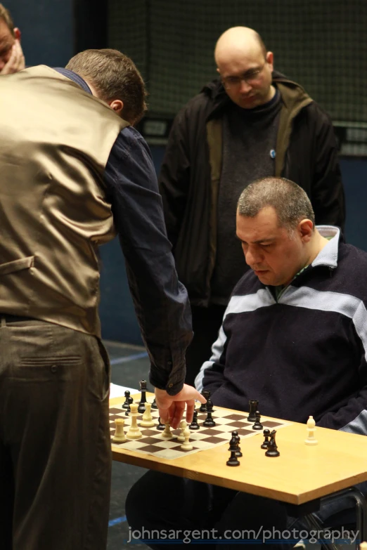 a man with a black jacket playing chess in a group