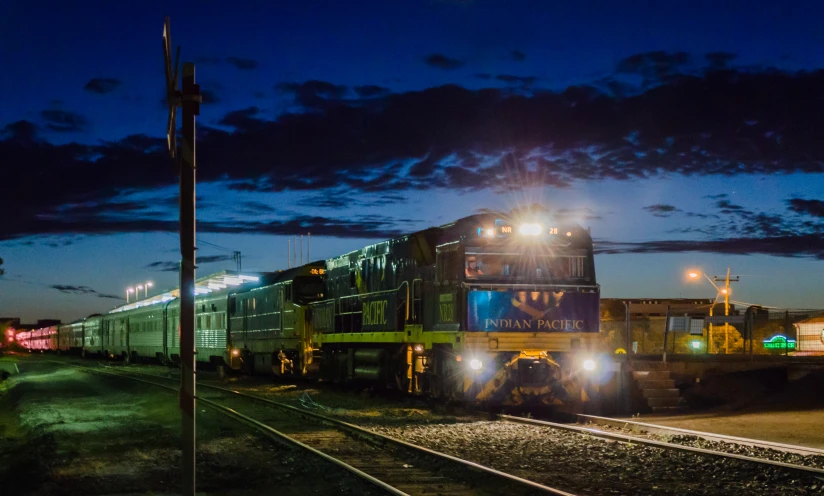 a train with headlights on traveling along tracks