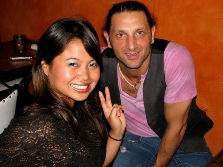 a man and woman posing for the camera at a restaurant