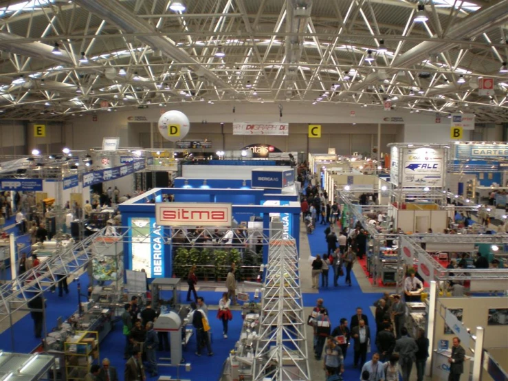 people walking around an exhibition hall near many large sets of trusses