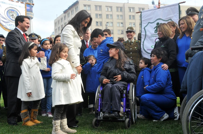 a little girl in a wheelchair standing next to an older woman