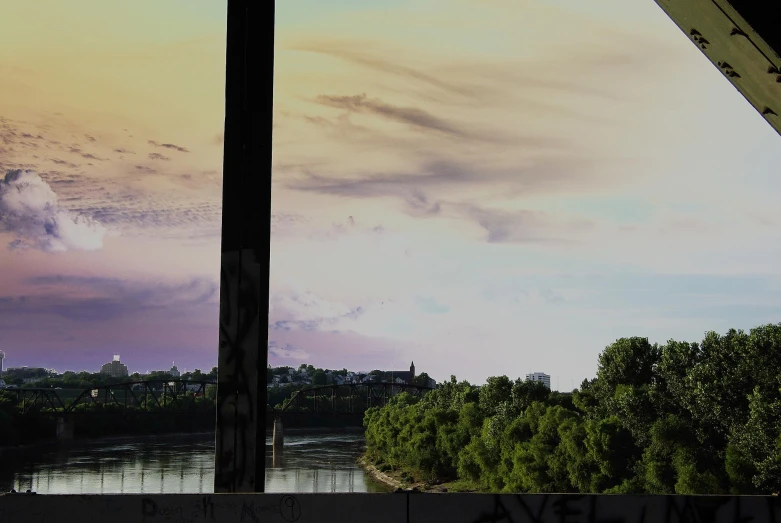 the view out a room shows an open river, trees, and a bridge