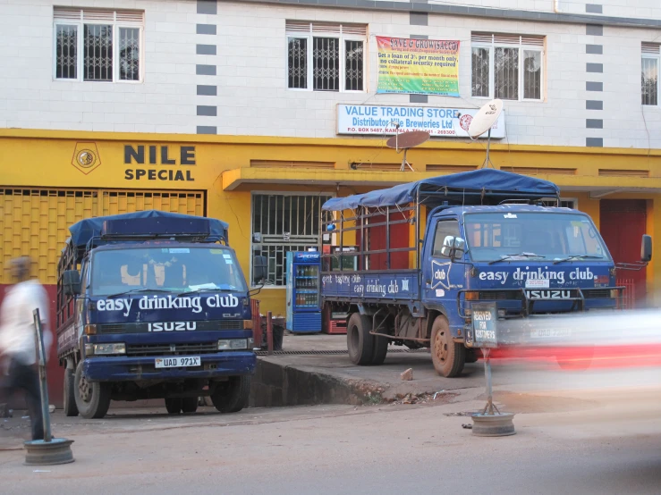 three blue trucks are parked outside in front of a yellow building