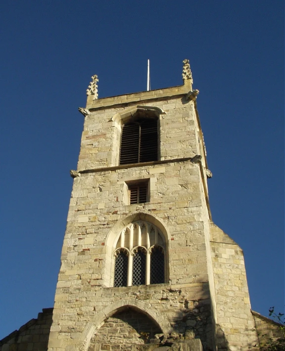 a tall clock tower has a flag at the top of it