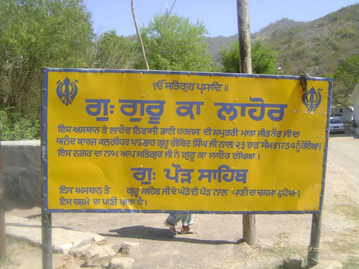 yellow and blue sign with foreign writing in rural area