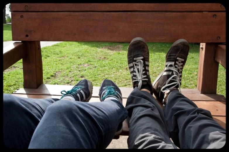 a pair of legs with converse shoes are sitting next to each other