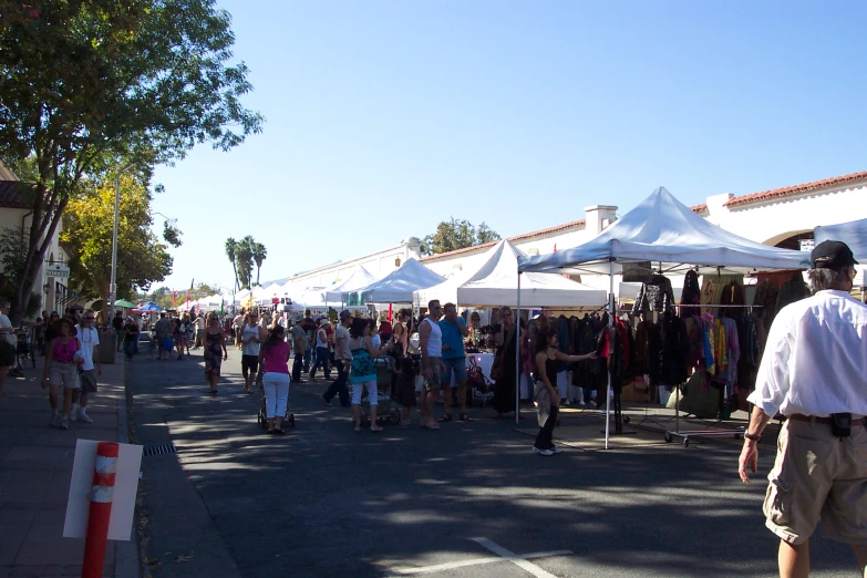 many people stand around a group of tents outside