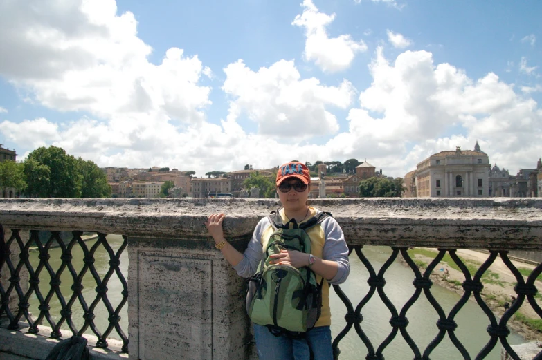 the man wearing a cap stands on a bridge