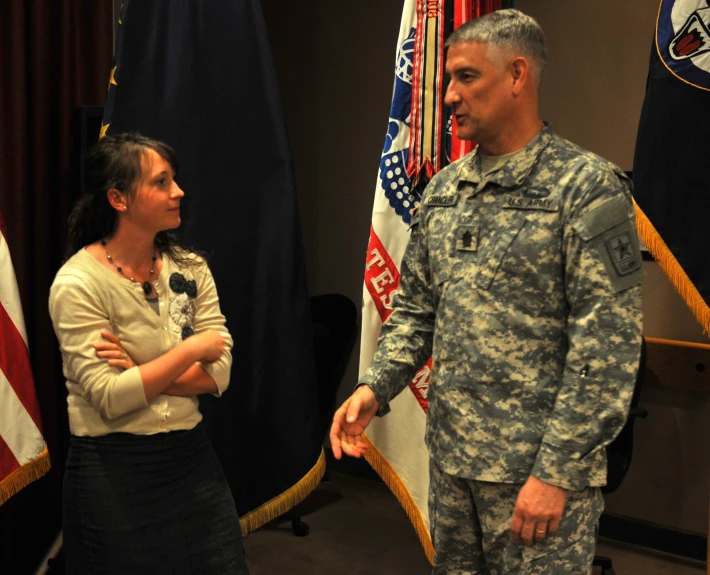 a soldier in uniform is greeting a woman