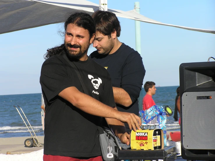 two men standing near the water in front of a tv