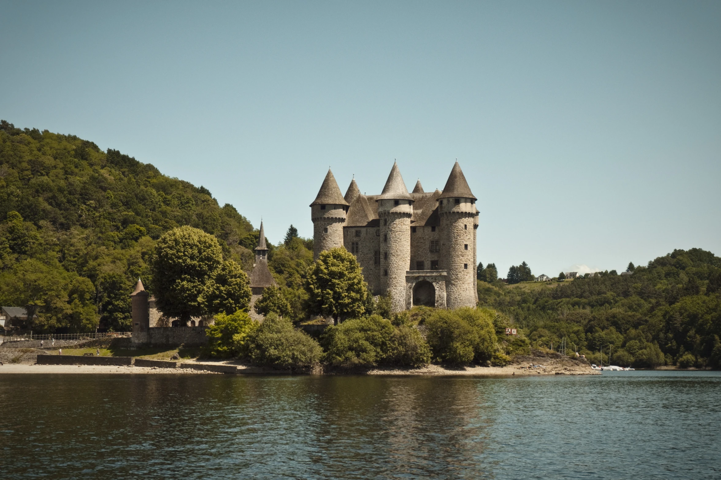 a castle in the middle of water on a hill side