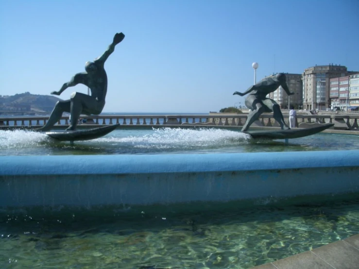 a statue sits in the water, with other sculptures