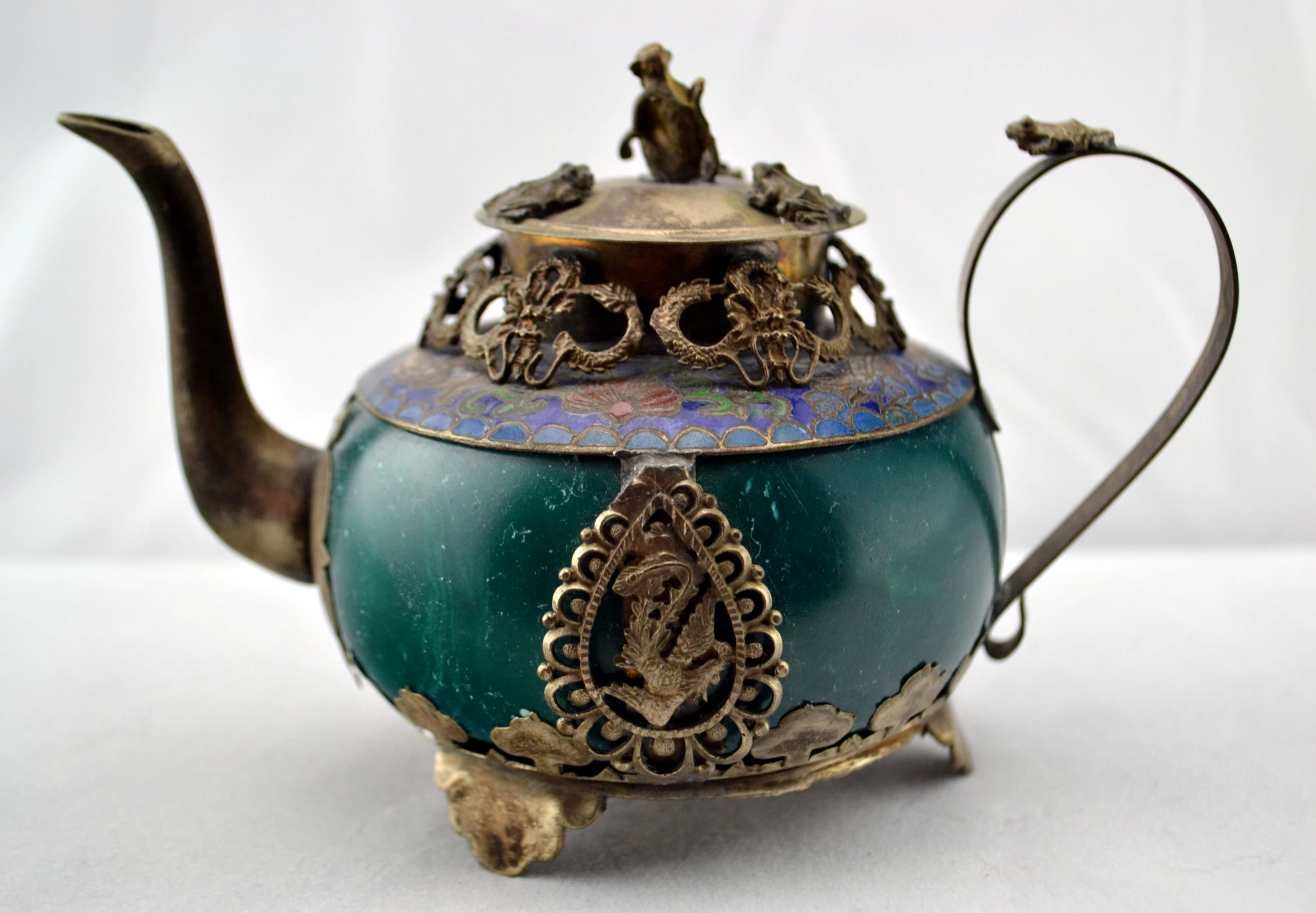 a teapot with a woman figurine sitting on top