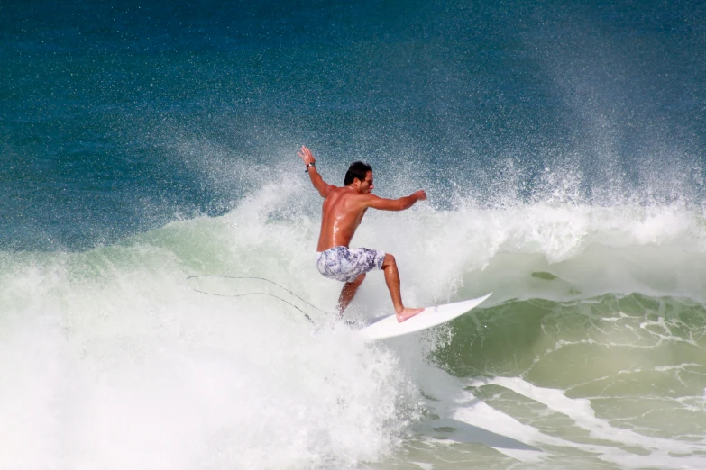 a man in white shorts surfing on an ocean wave