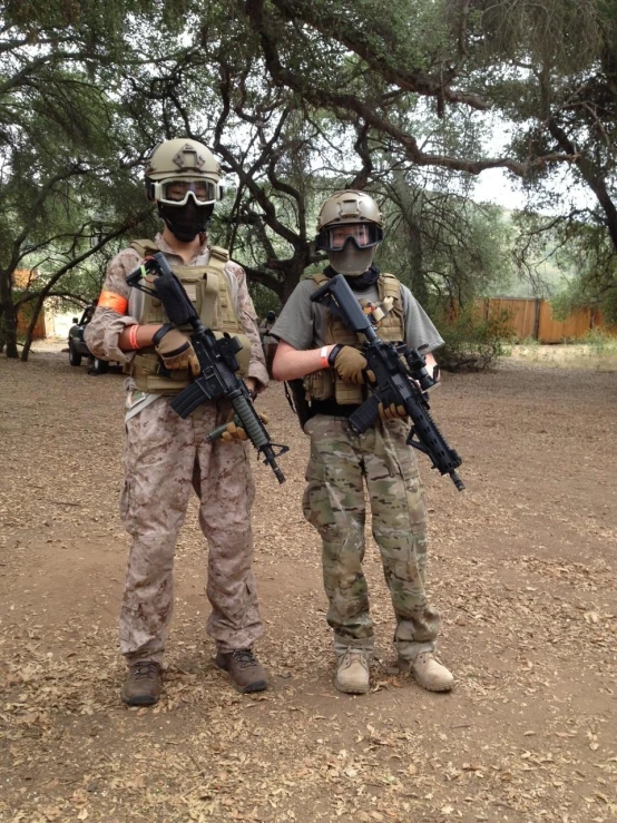 two soldiers with guns are standing in a dirt field