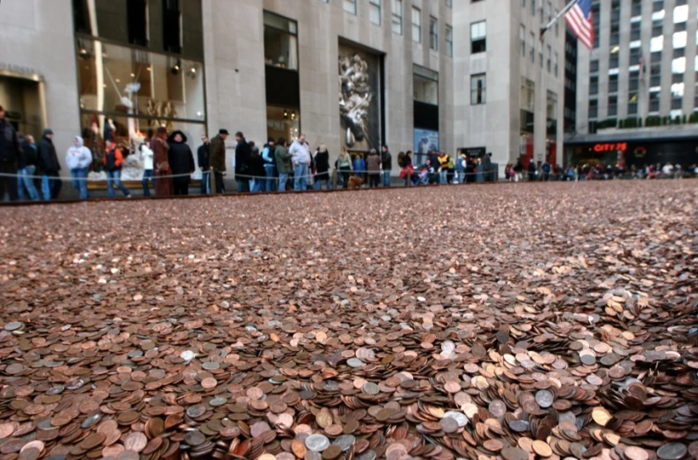 a crowd of people standing in a row with lots of penn bills on the ground