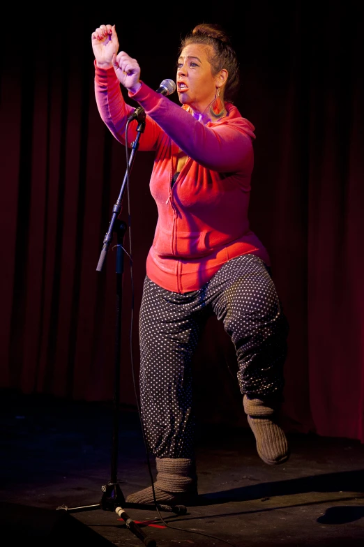 an older woman stands at the microphone while singing