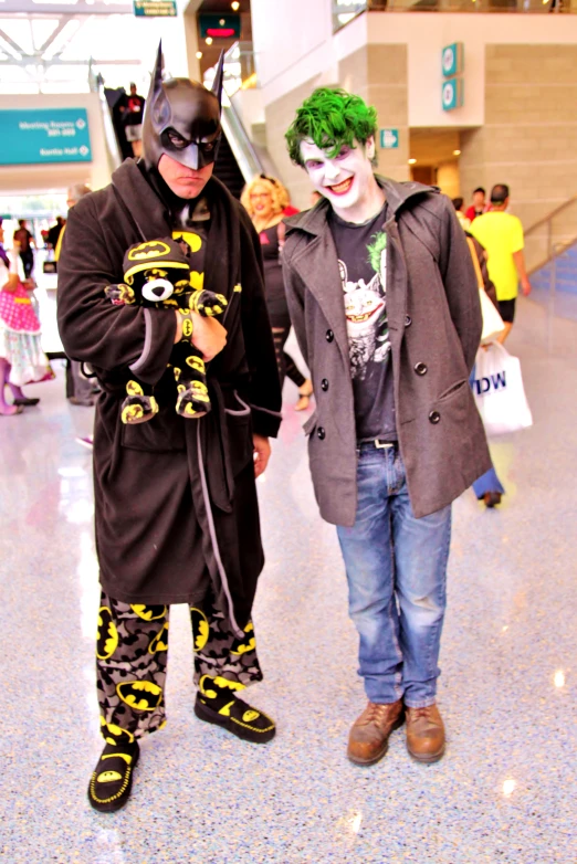 two men dressed as batman and robin wayne are standing in an airport