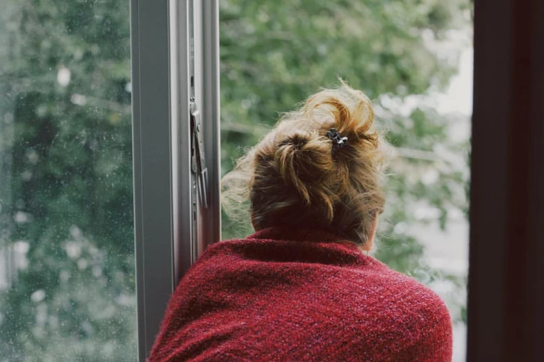 a lady wearing a red shawl looking out of a window