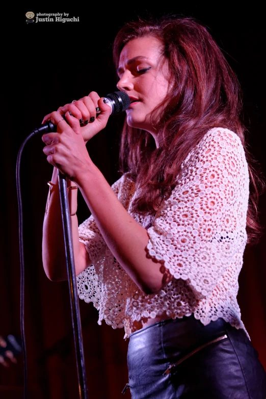 a woman is singing in a concert with a microphone