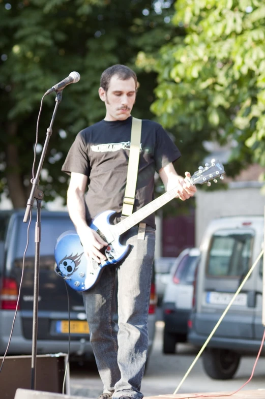 a man standing next to microphones playing guitar