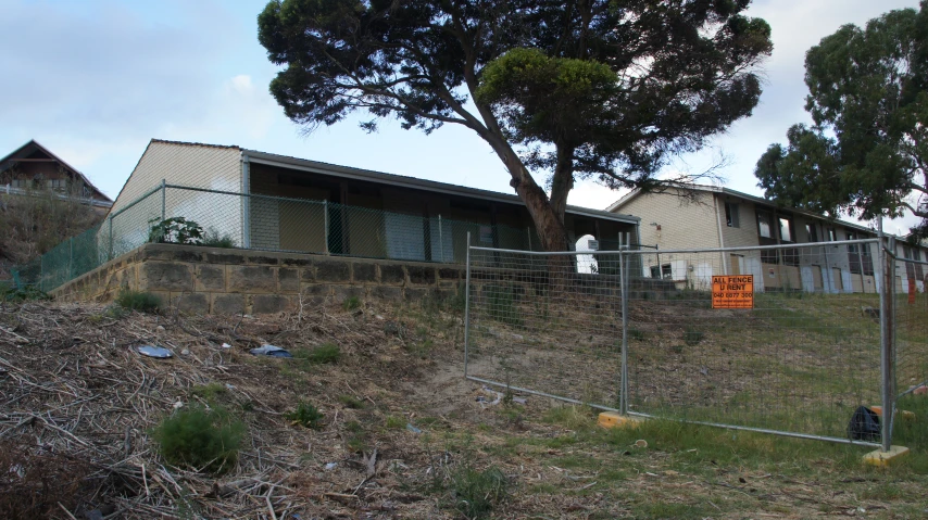 a home behind a chain link fence on top of a hill