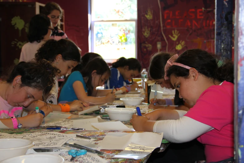 a group of children at a table writing on papers