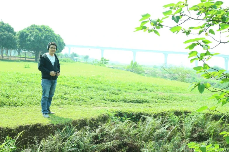 man standing on grassy slope with water in background