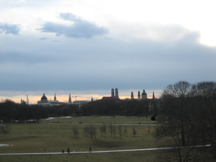 a landscape view with people walking on the grass in front of a skyline