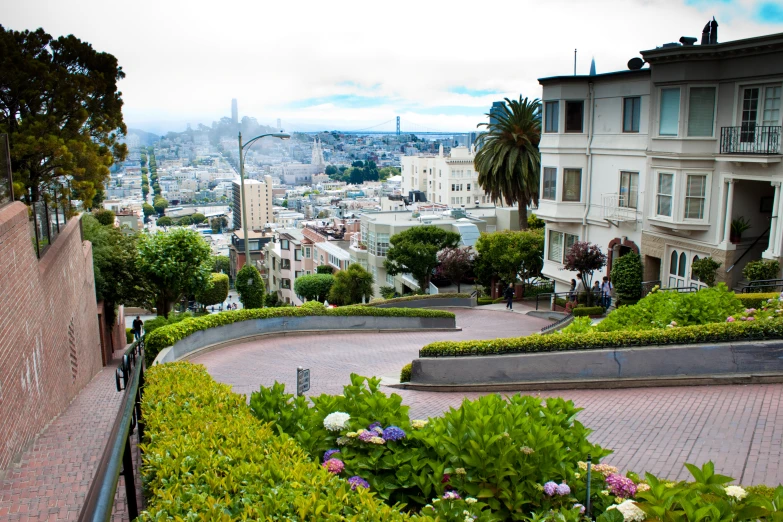 an empty bench on a pathway in front of houses with mountains in the background