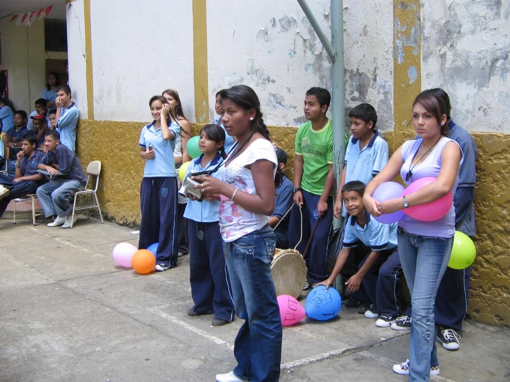 a group of young children stand outside in front of a line of people