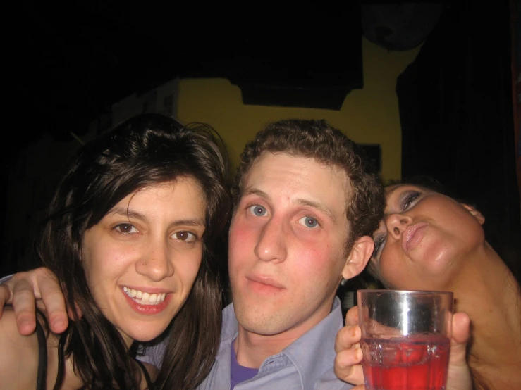 the man and two women are holding a red drink