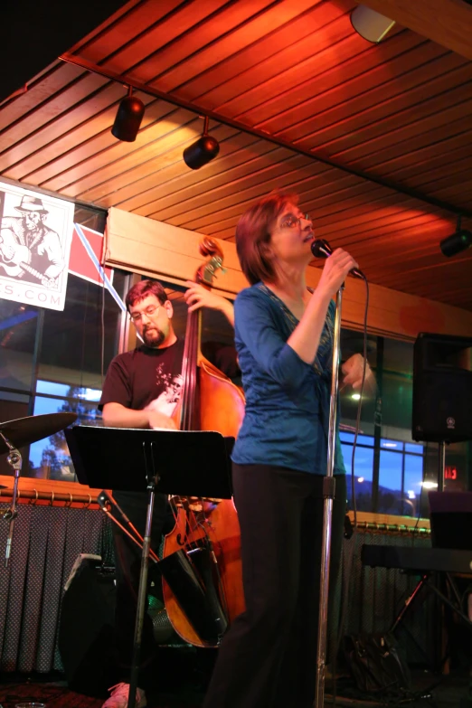 woman singing on stage with musician in the background