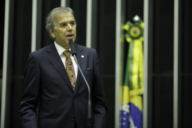 a man in suit and tie speaking from a microphone