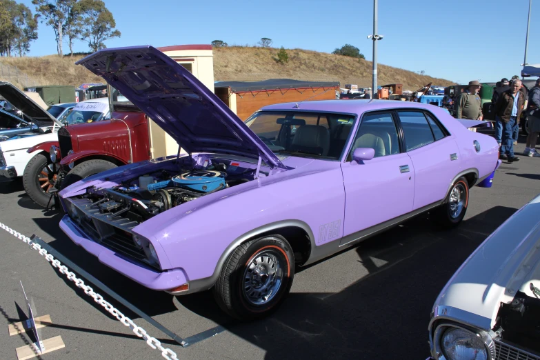 purple muscle car sitting on the side of a road