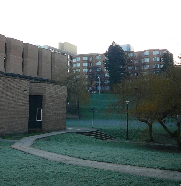 an empty building with grassy area next to the sidewalk