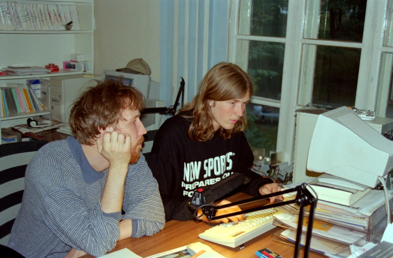 a young man sitting next to a woman in an office